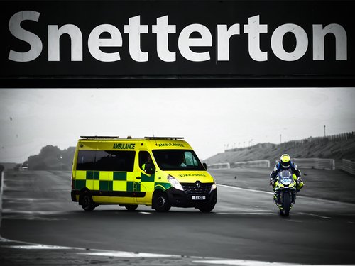 An EAMC emergency ambulance providing event medical and first aid cover at Snetterton Raceway with a motorbike racing past